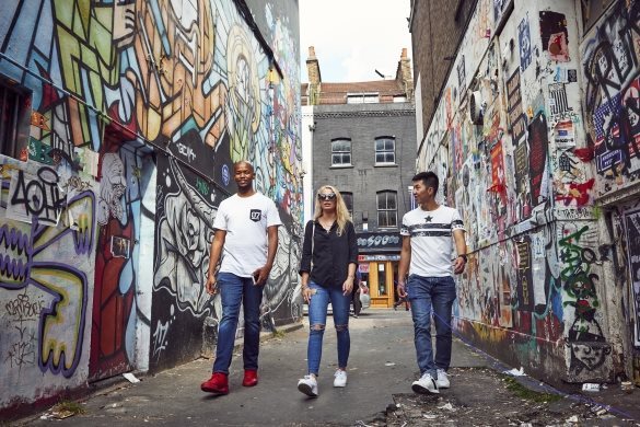 Three people walking down a street with graffiti