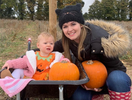 A woman smiling with her child in a pumpkin patch