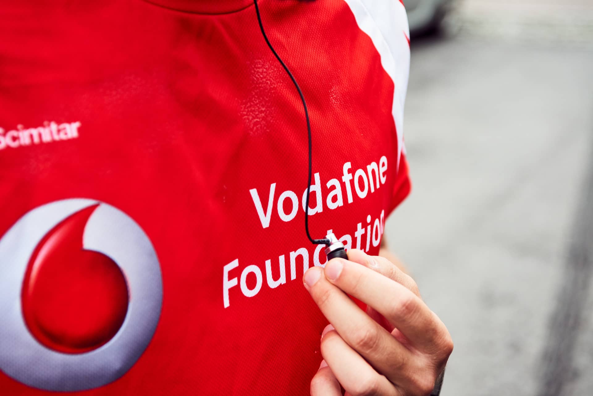 A man on a run outside with a Vodafone Foundation top on