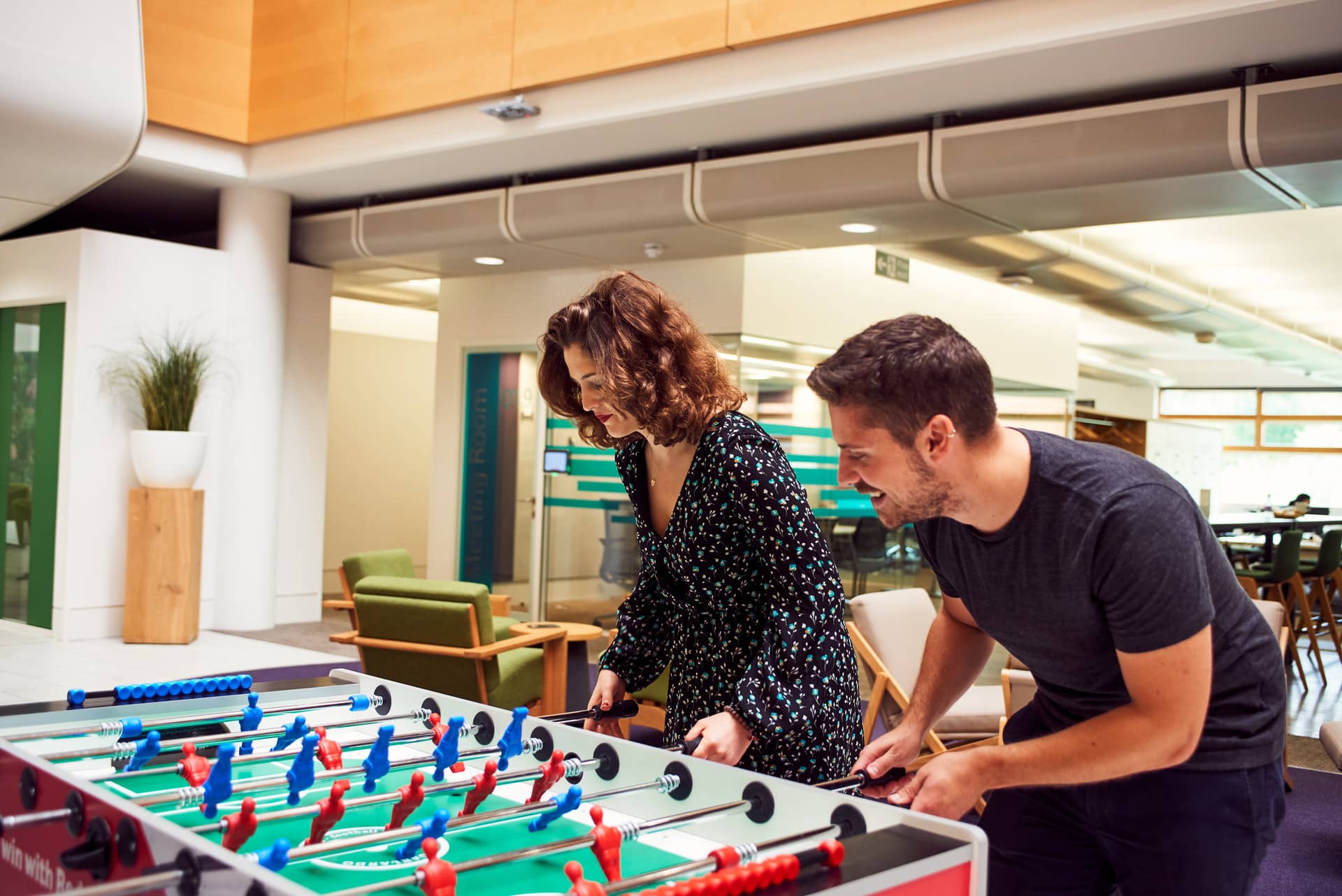Two people playing a game of foosball in the office