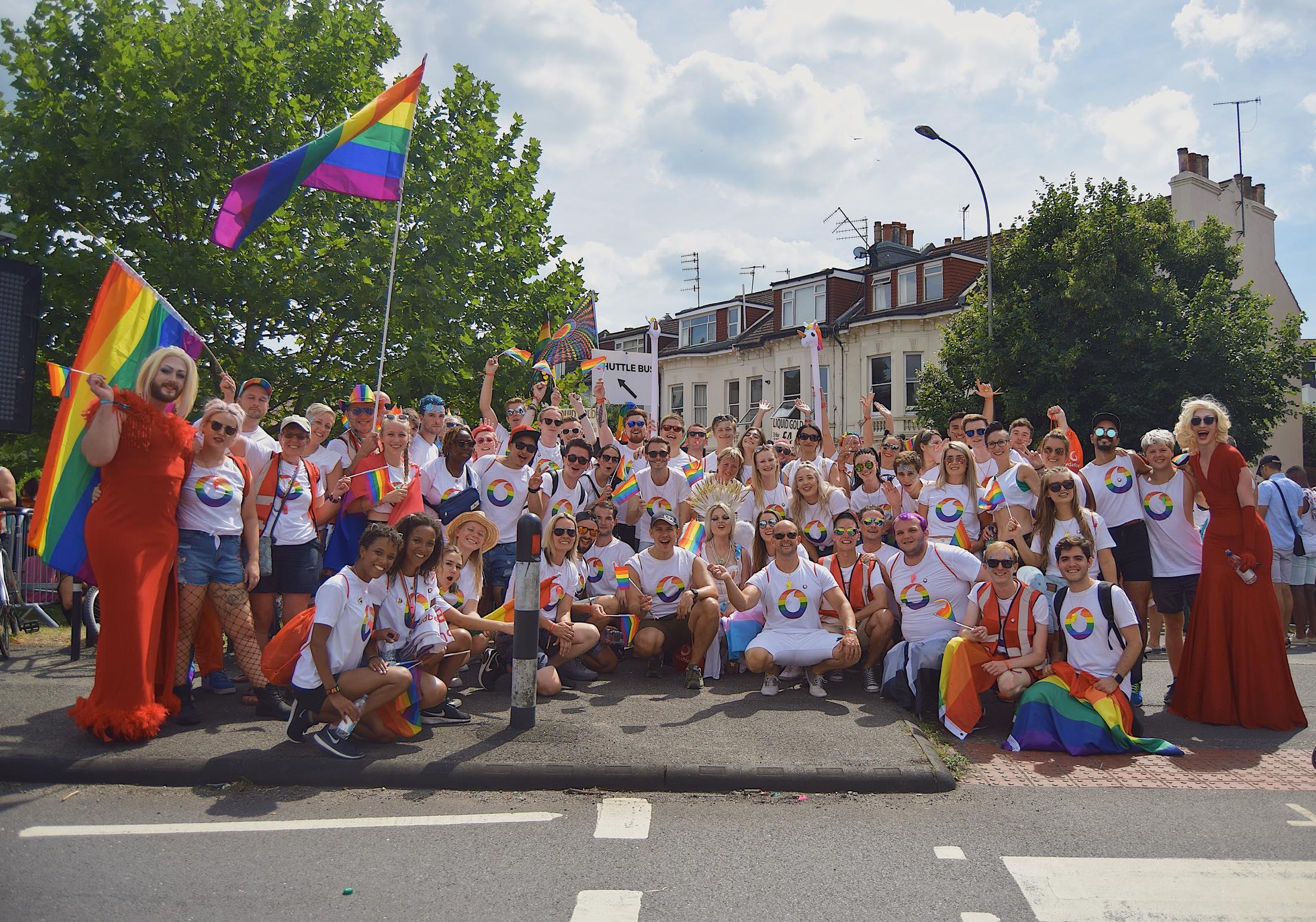 A group of people in LGBT vodafone branded tops and flags at a pride event