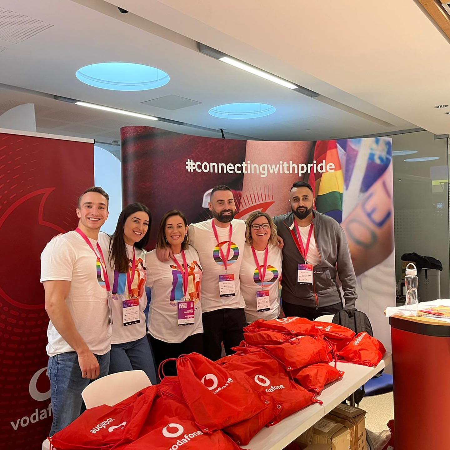 group of people in LGBT vodafone branded tops at a student event with #connectingwithpride banner
