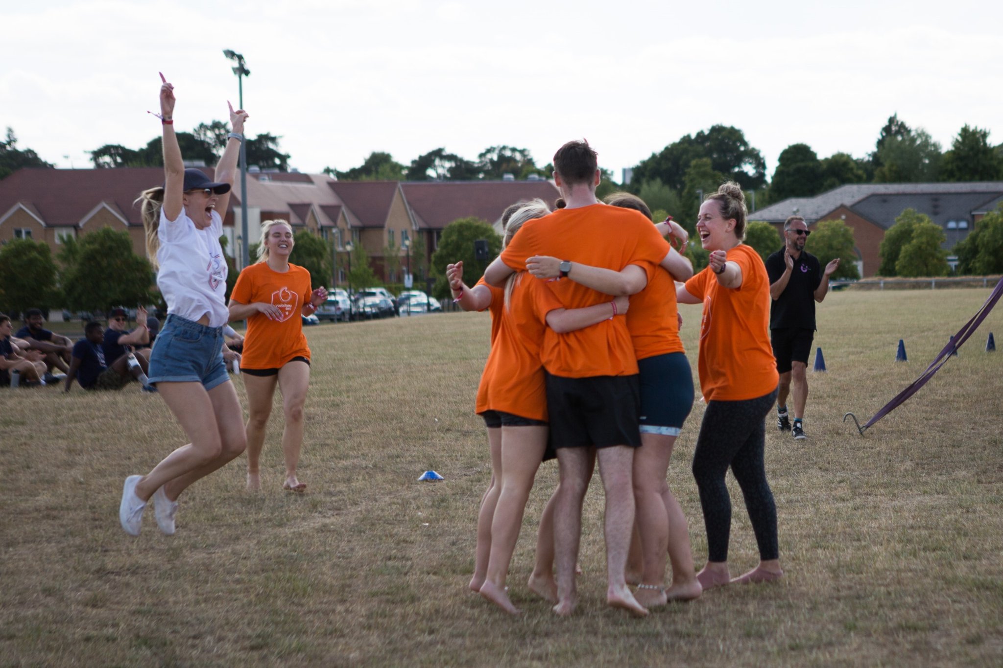 A team of people in orange shirts hugging after a sports win