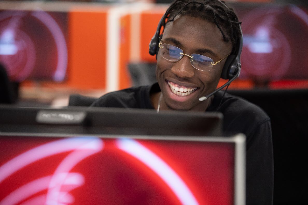 A man smiling whilst sat at his desk wearing a headset