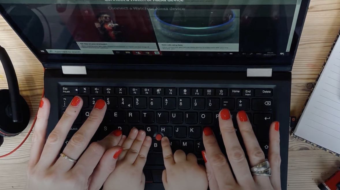 A woman typing on her laptop with her children's hands in the image too
