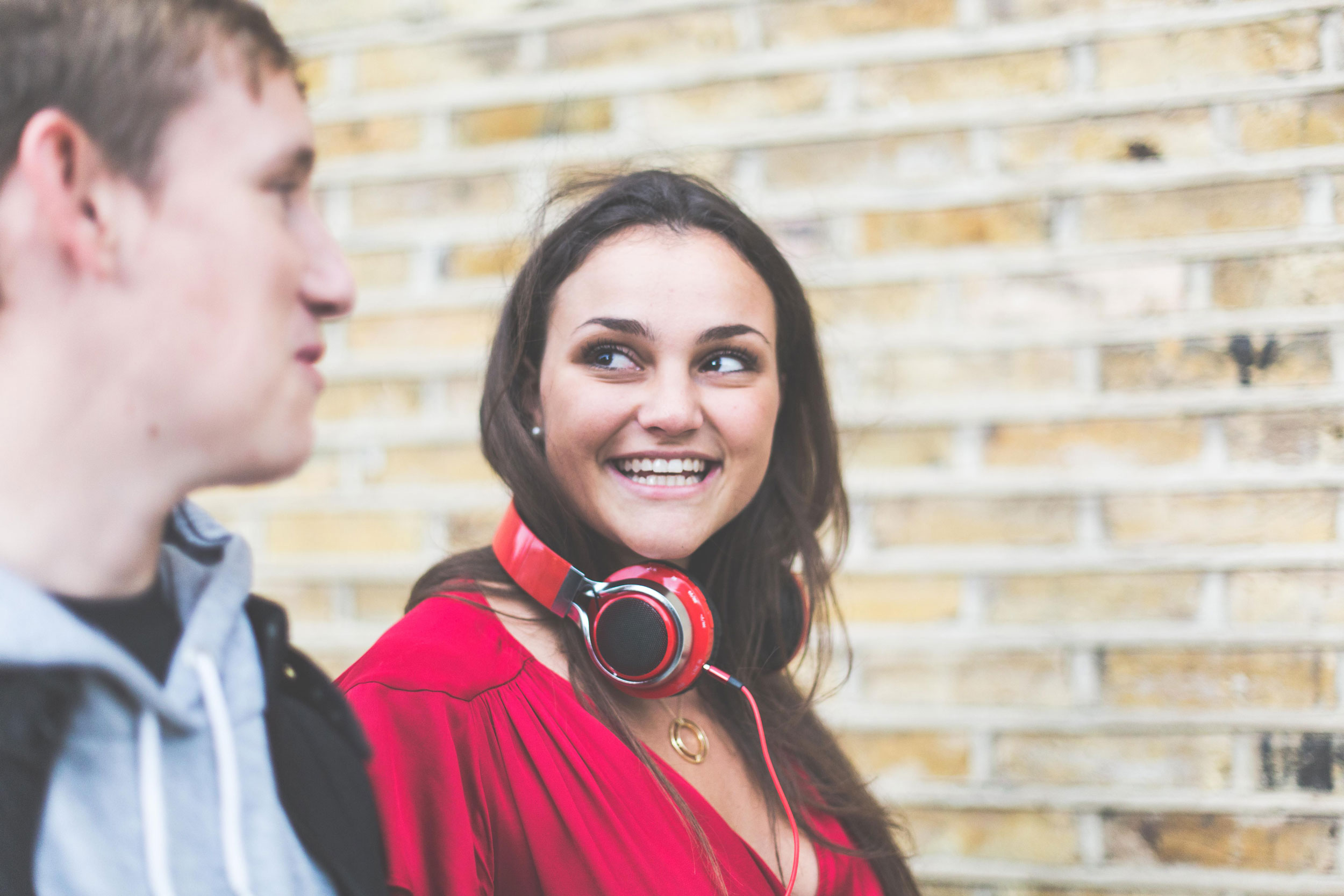 A woman smiling at another person wearing red headphones