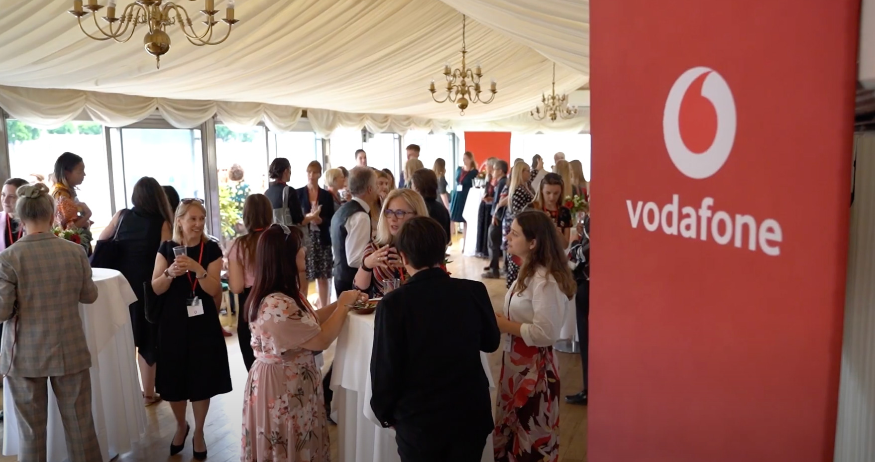 A group of people at an event inside with Vodafone branding