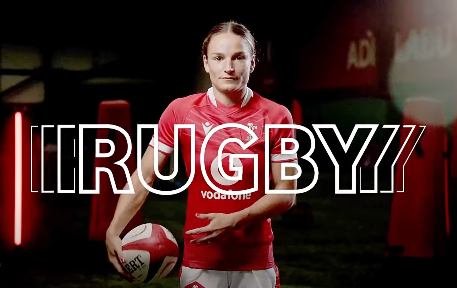 Aa woman in a welsh rugby top with a rugby ball with the word RUGBY on the front