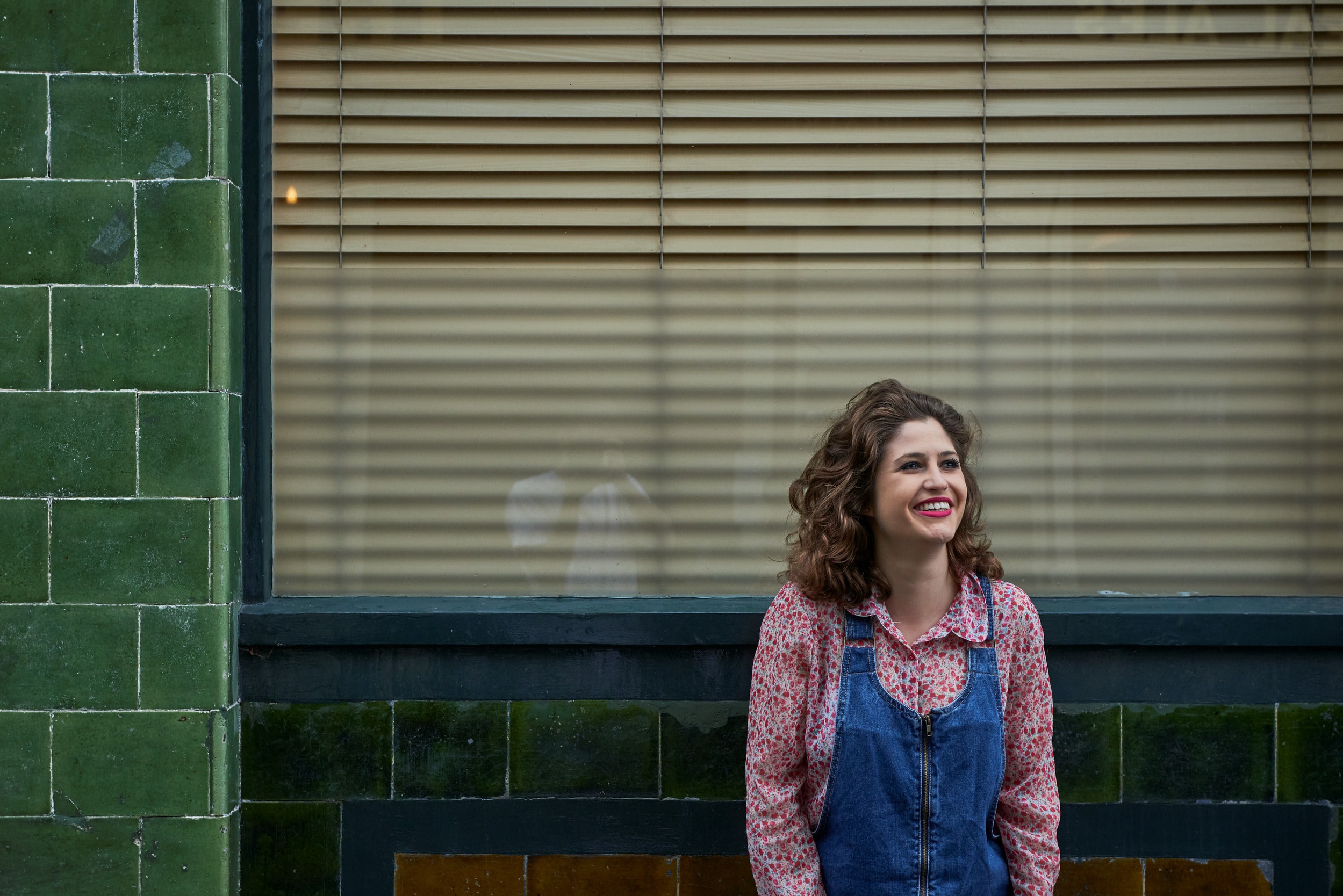 A woman smiling outside a window