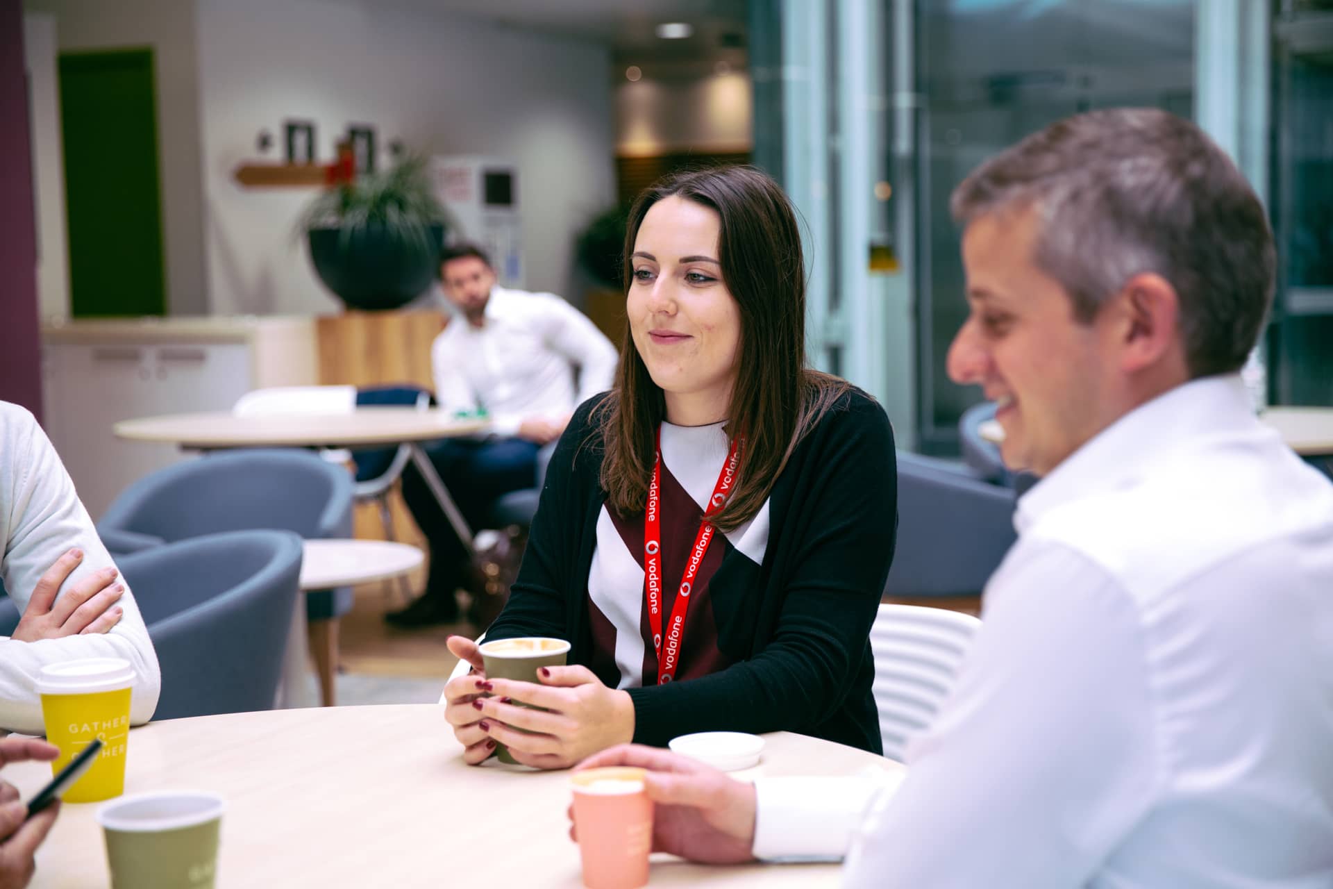 A group of people chatting at a desk with coffees