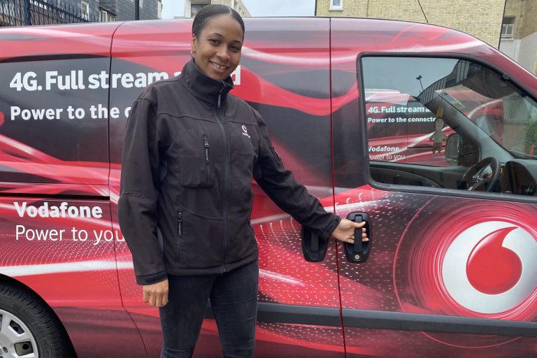 A person smiling next to a vodafone branded car