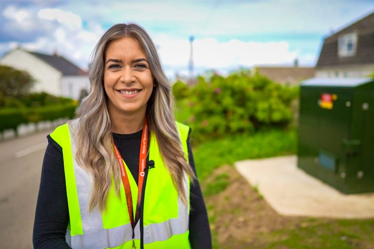 A woman smiling with a high vis jacket on