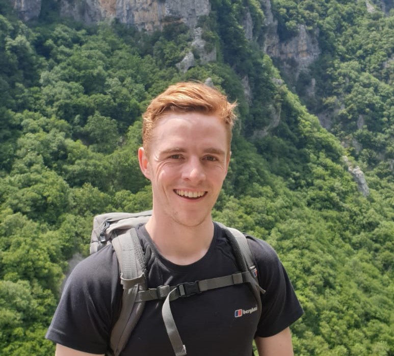 A man smiling on a hike in the outdoors