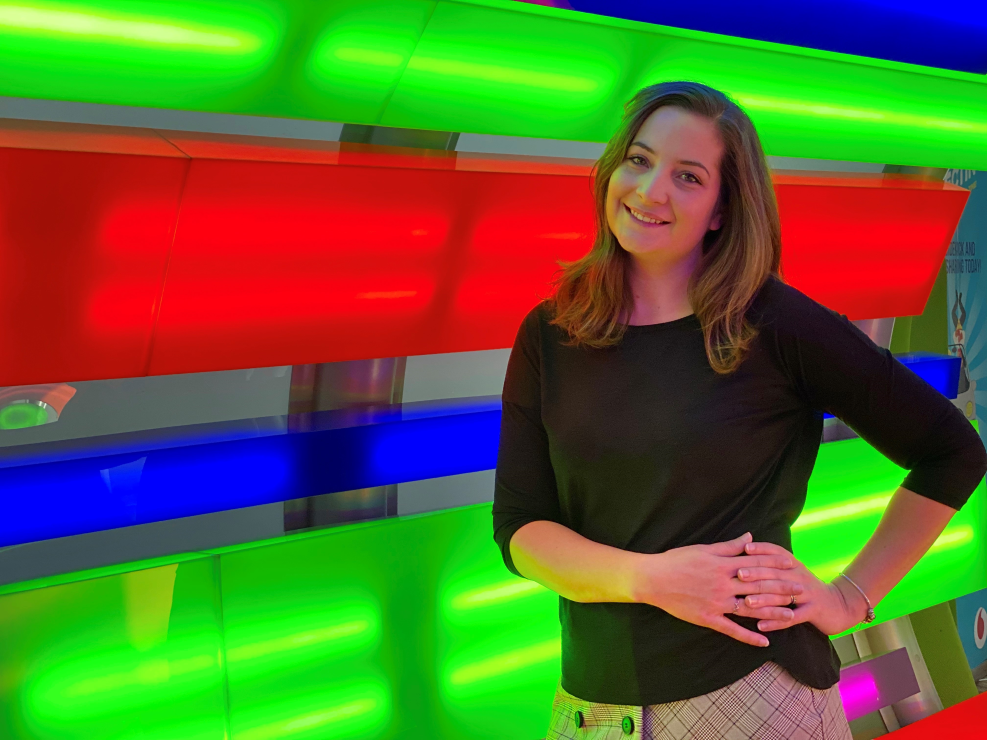 A woman smiling with green, red and blue lighting behind her