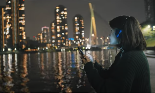 Image of a woman on her phone in front of a river/cityscape