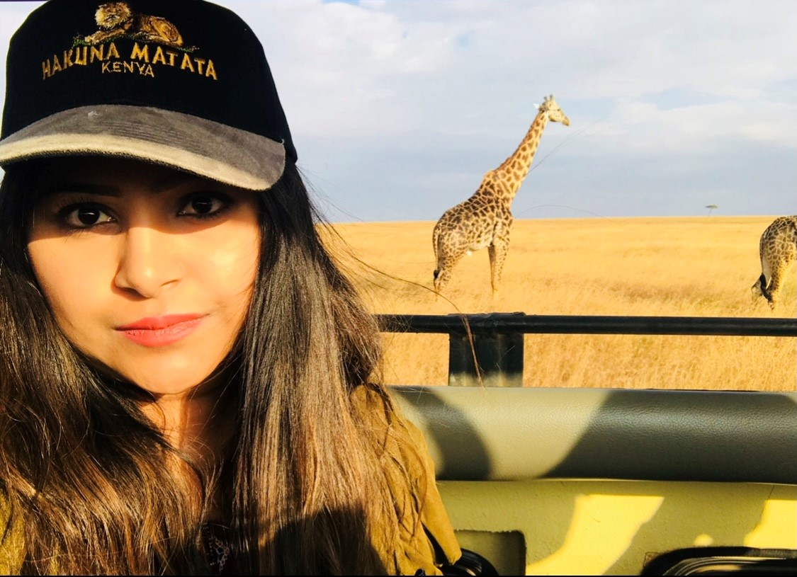 A woman in a truck on a safari with giraffes in the background