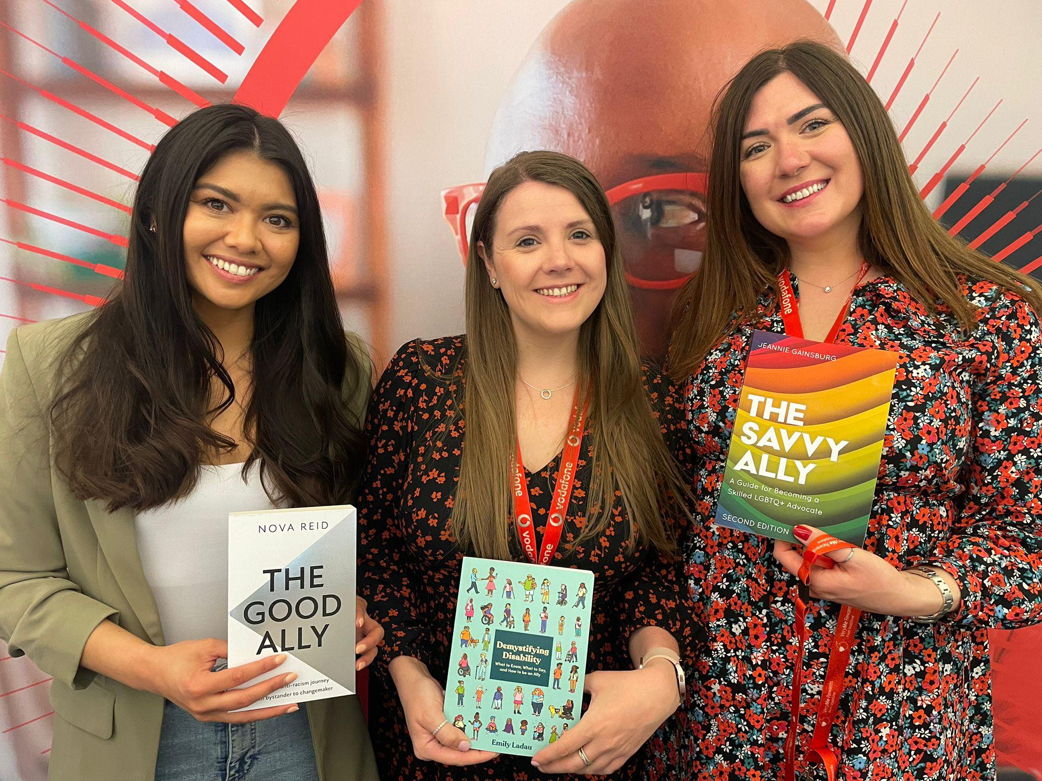 A group of women smiling whilst holding ally books