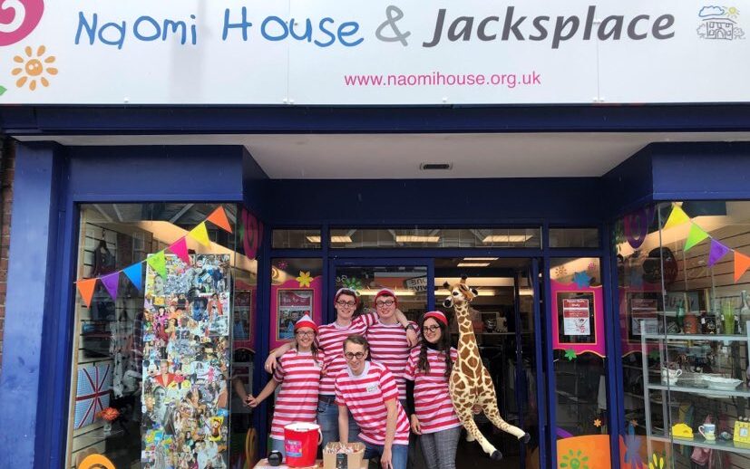 Group of people smiling outside a building on a charity day