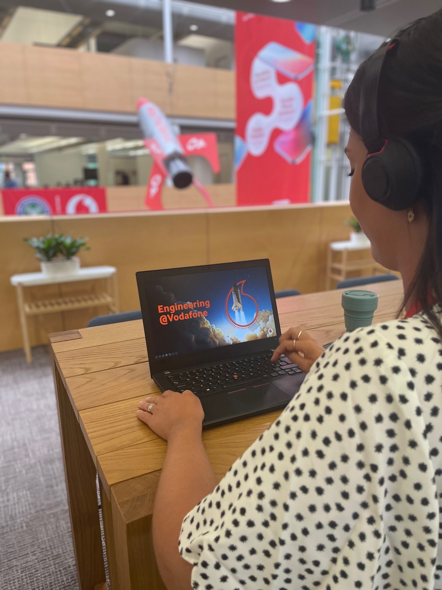 A woman looking at a laptop reading 'Engineering at Vodafone' in the office