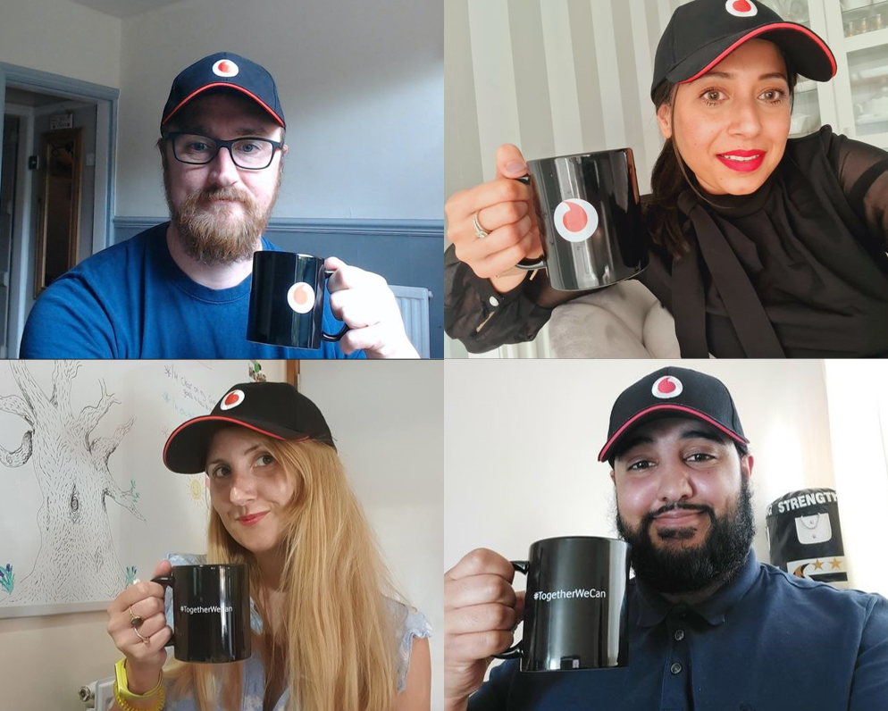A group of people smiling with Vodafone branded hats and mugs