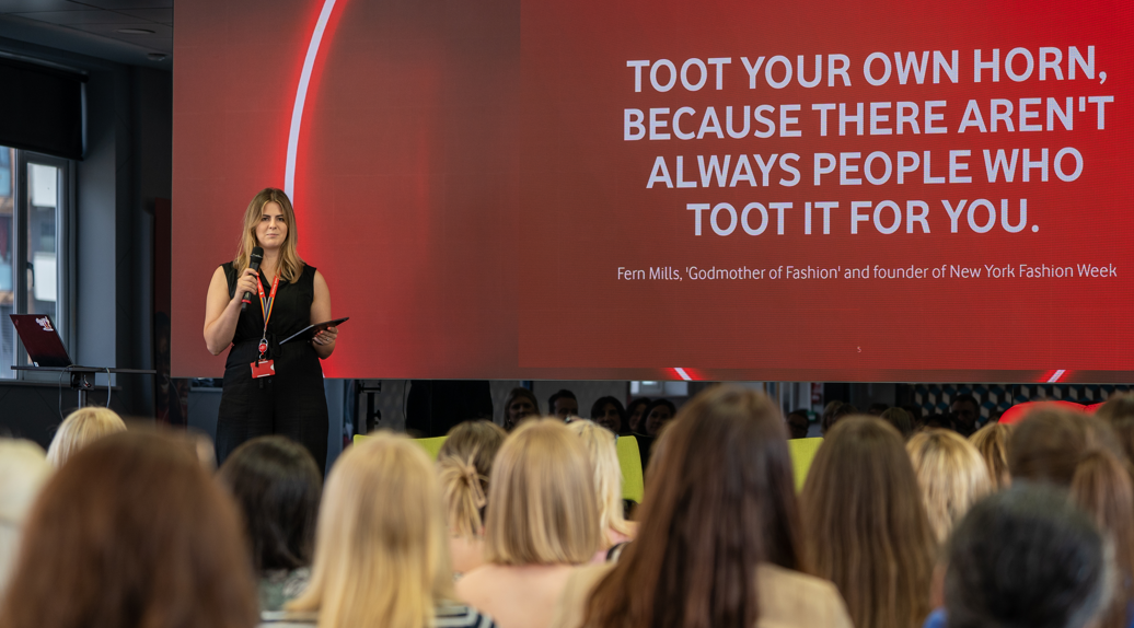 A woman presenting at an internal event with a crowd of people