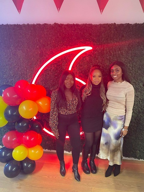 Three women standing in front of Vodafone branding with a balloon display at an internal event